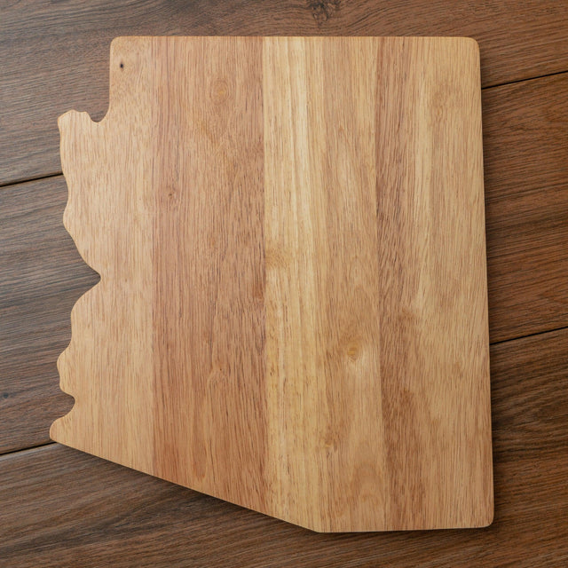 Arizona-shaped cutting board standing upright on a wood table.