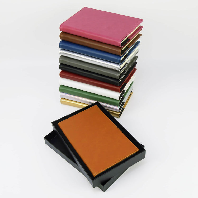 Stacked journal colors beside an open black presentation box.