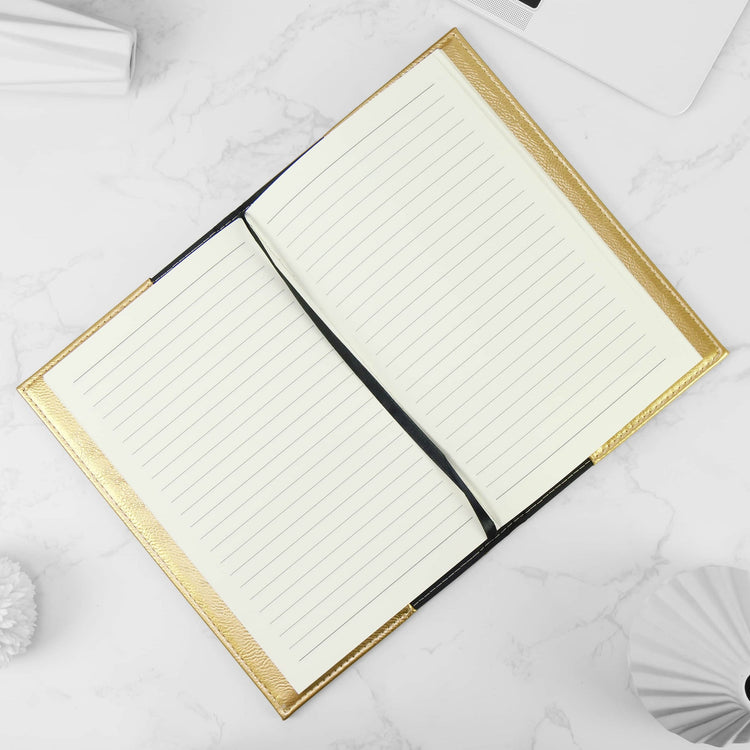 Gold journal notebook open to lined pages on a marble surface.