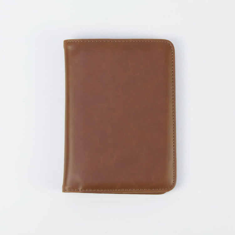Brown passport wallet shown closed against white.