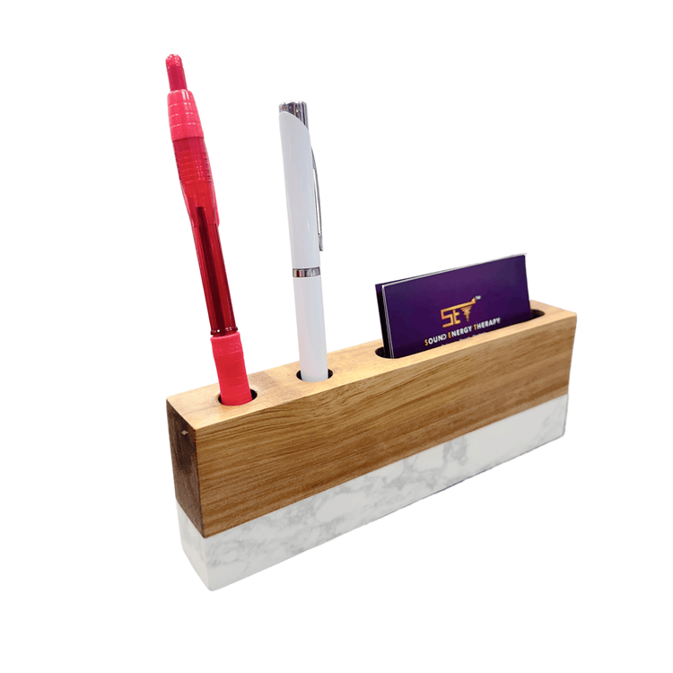 Desk organizer holding two black pens and a black business card.