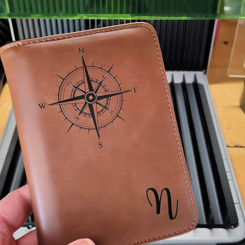 Rawhide passport wallet engraved with a compass design and monogram.
