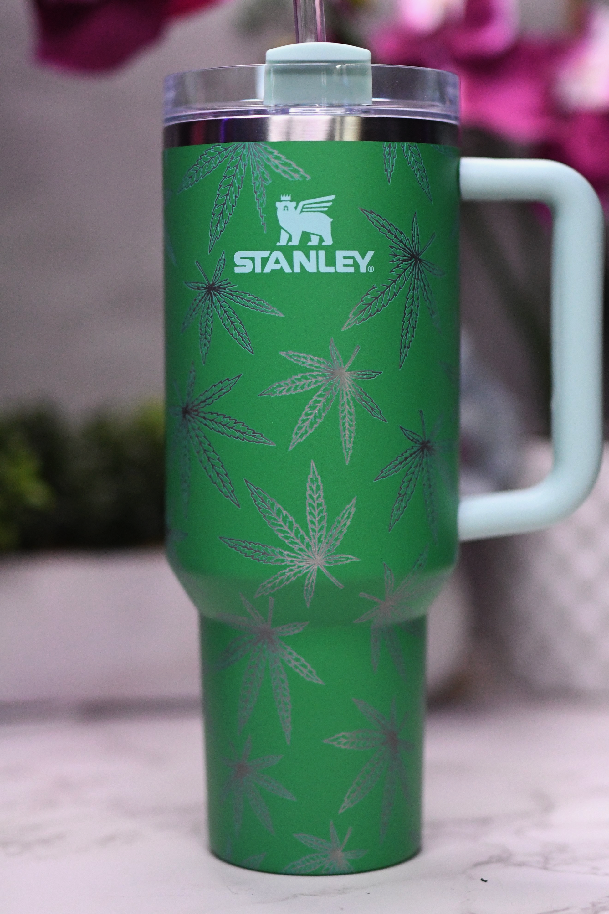 a green travel mug with a straw sticking out of it