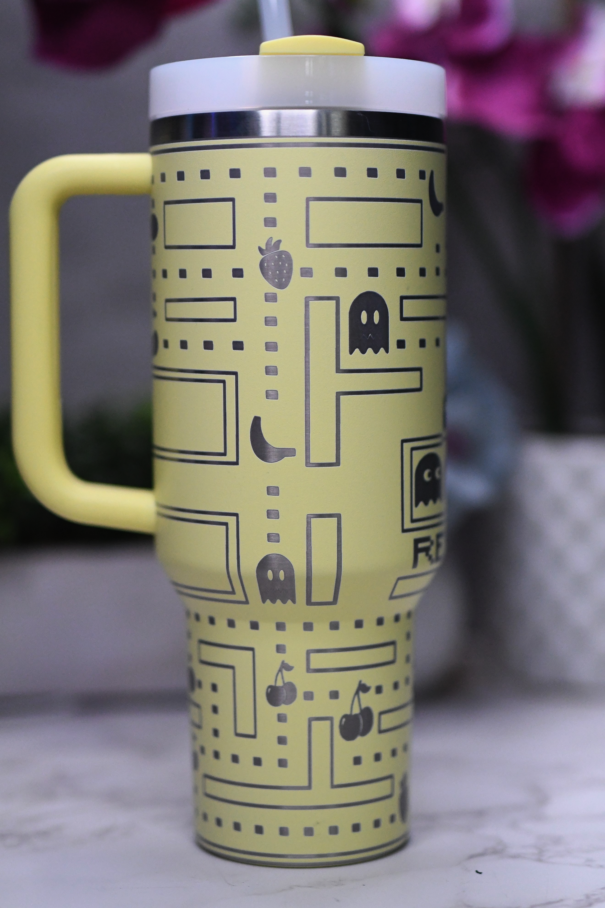 a yellow travel mug with a pacman pattern on it