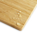 Water droplets beading on the bamboo cutting board surface.