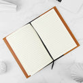 Rawhide journal notebook open to its lined cream pages.