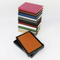 Stacked journal colors beside an open black presentation box.
