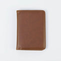 Brown passport wallet shown closed against white.