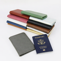 Assorted passport wallet colors stacked beside an open wallet and passport.
