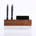 Desk organizer holding two black pens and a business card.