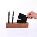 Desk organizer holding two pens and a purple business card.