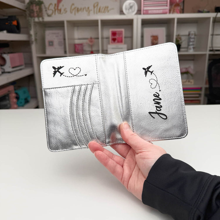 Silver passport wallet engraved with a personalized travel design.
