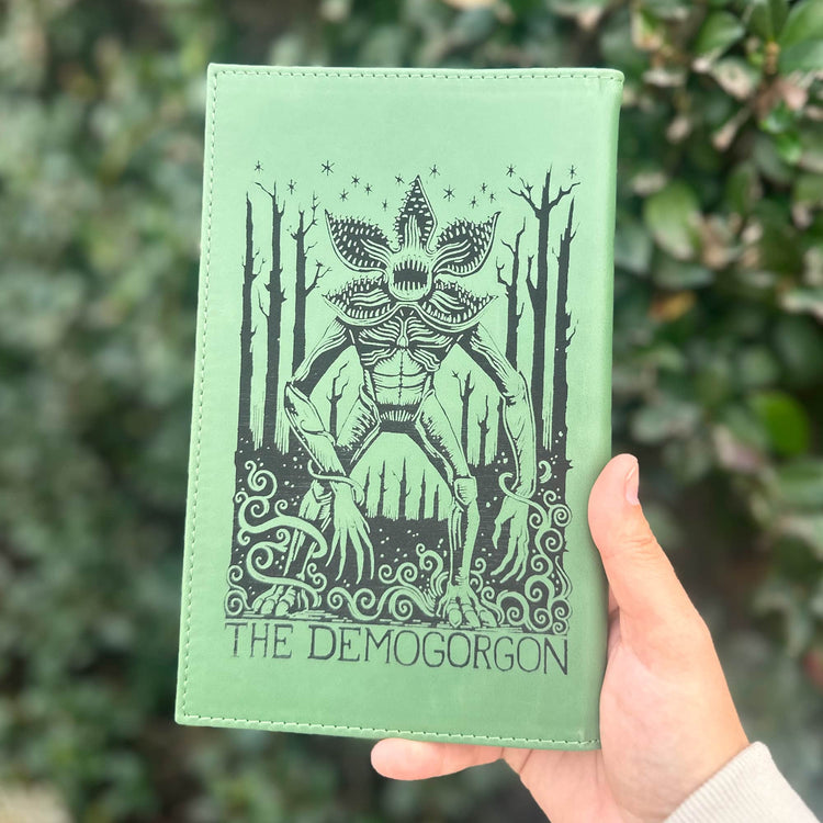 Green engraved journal held outdoors to show a detailed cover design.
