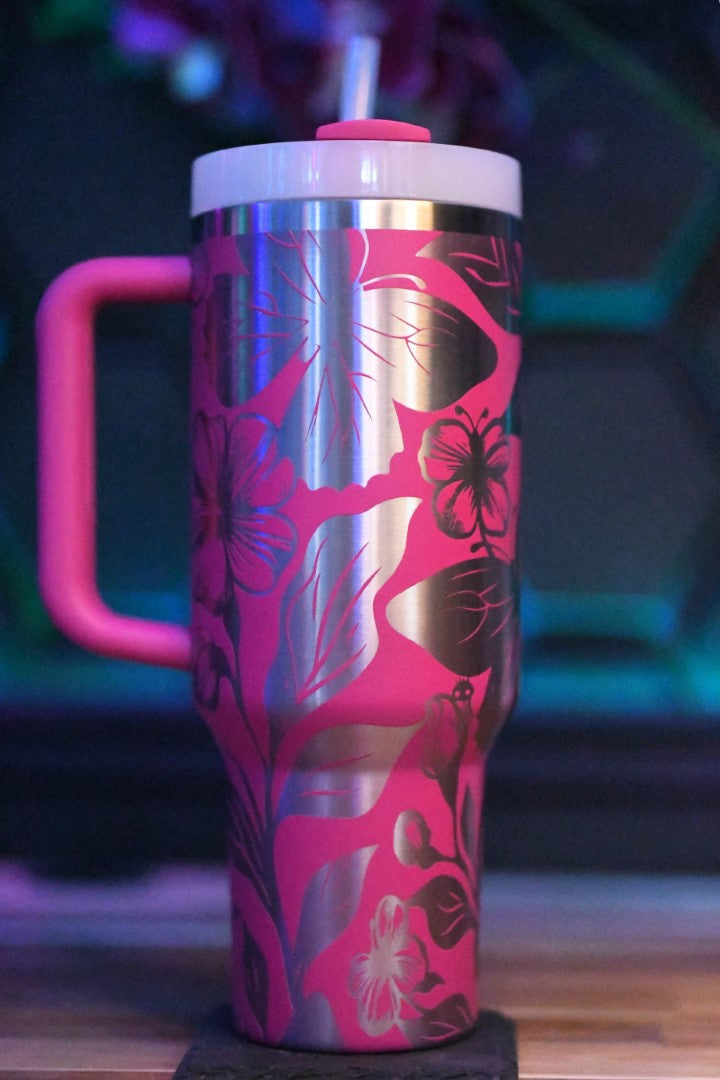 a pink and silver travel mug sitting on top of a wooden table