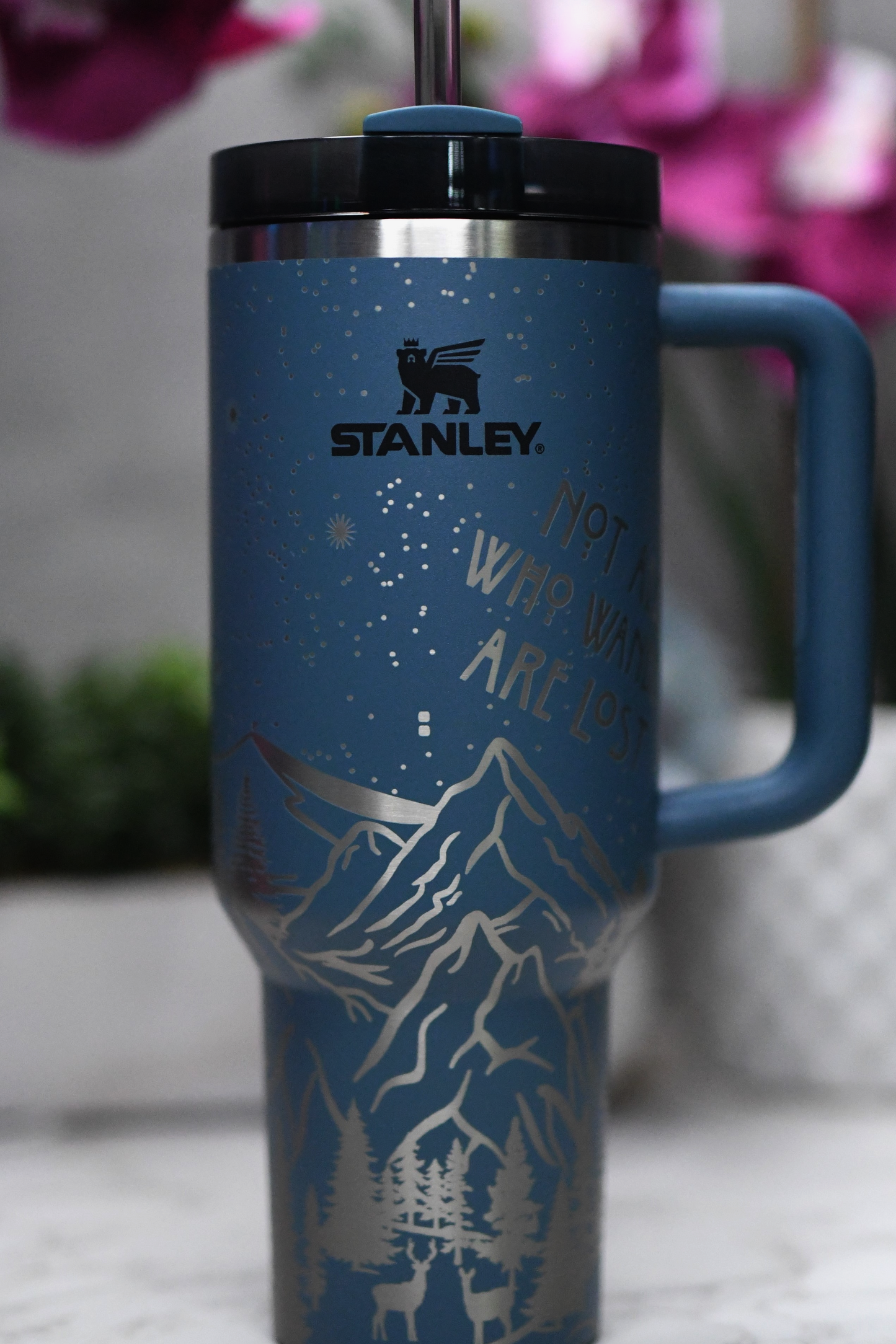 a stainless steel travel mug with a blue handle