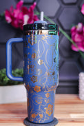 a blue and gold travel mug sitting on top of a wooden table