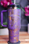 a purple and gold travel mug sitting on top of a wooden table