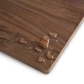 Water droplets beading on the walnut cutting board surface.