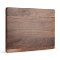 Solid walnut cutting board shown upright against white.