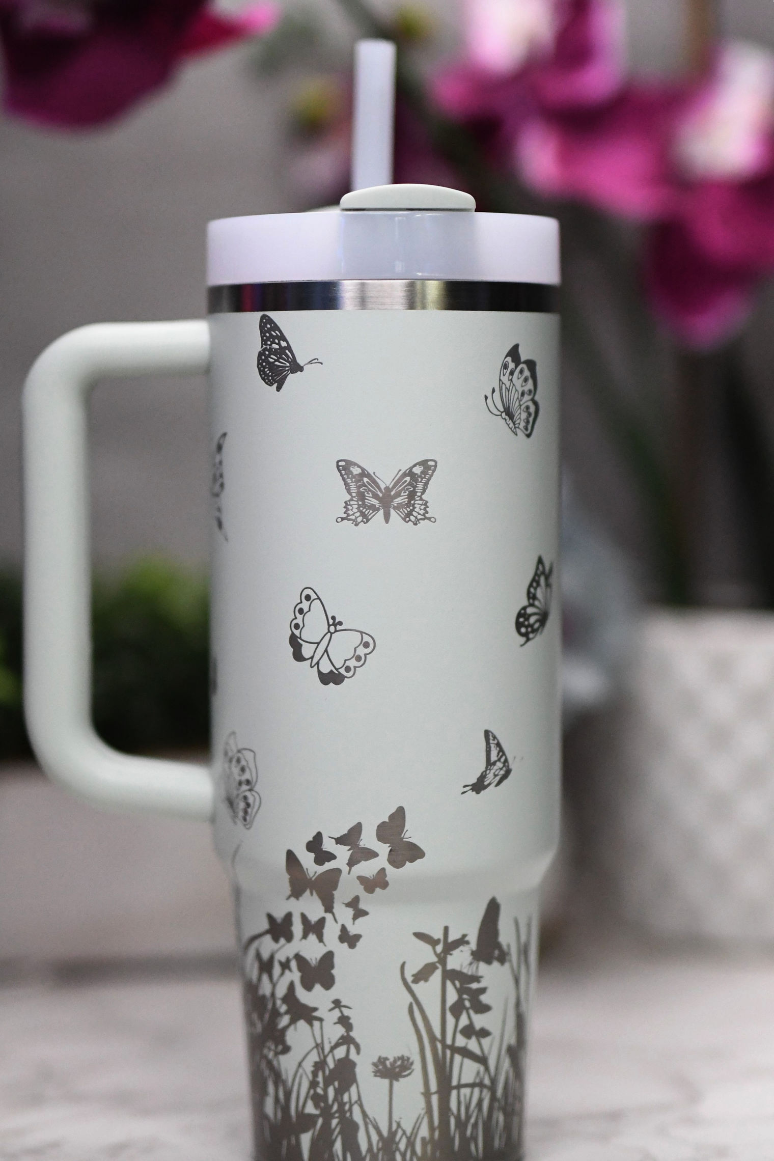 a white travel mug with butterflies on it