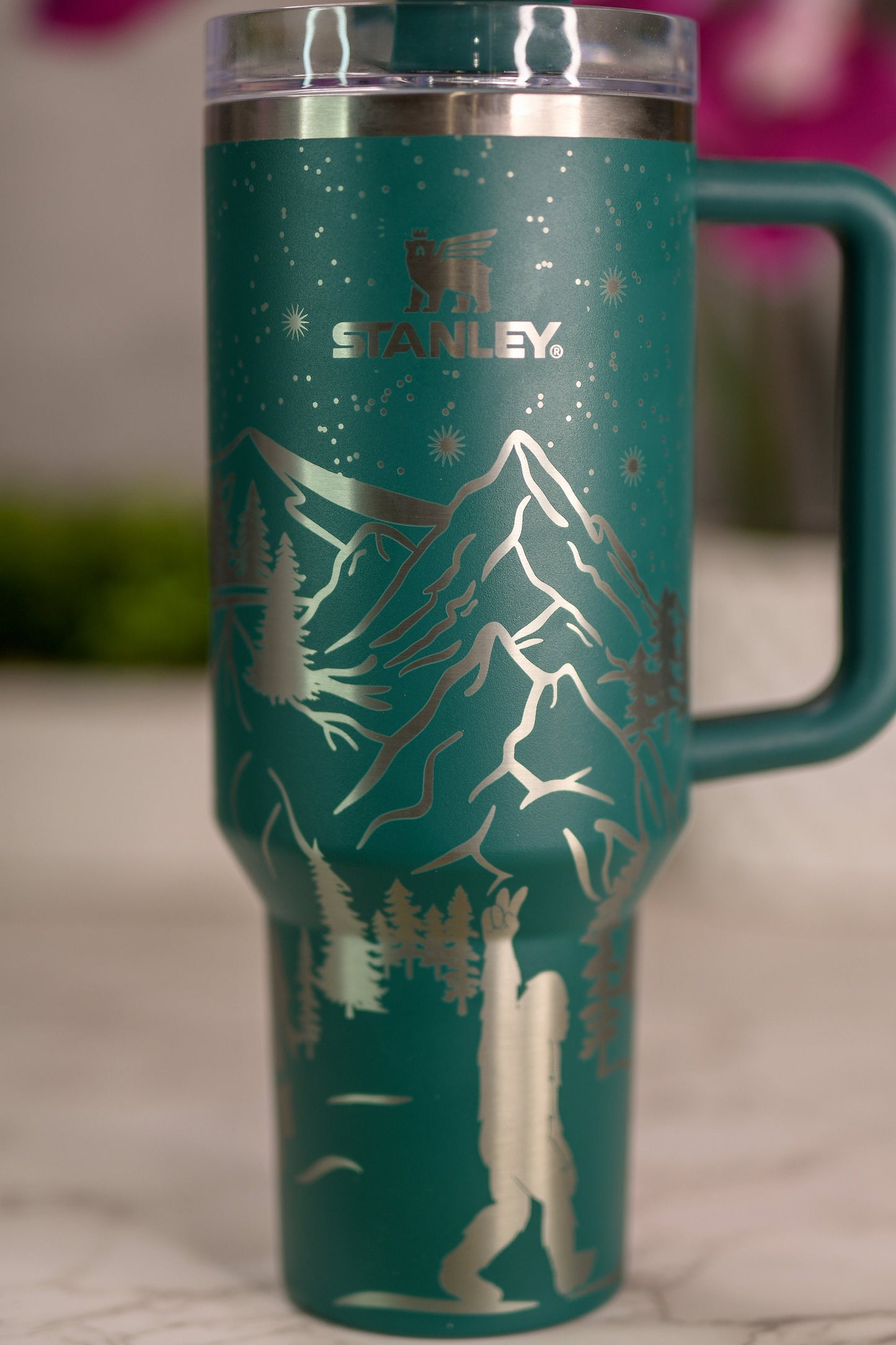 a green travel mug with a mountain scene on it