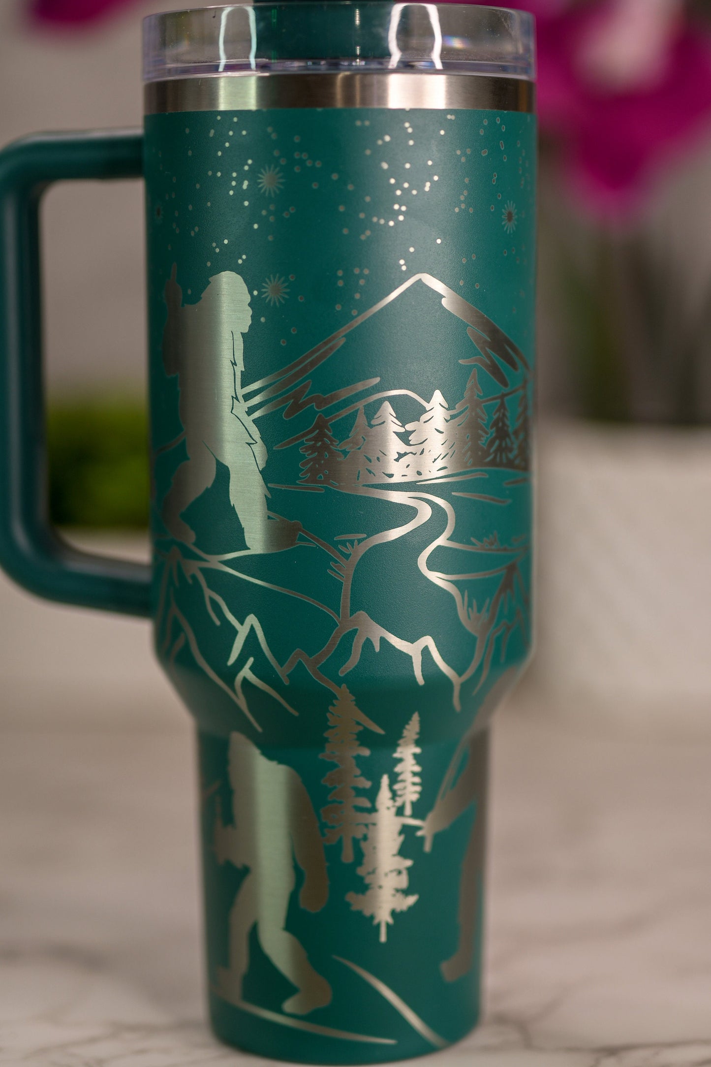 a green travel mug with a mountain scene on it